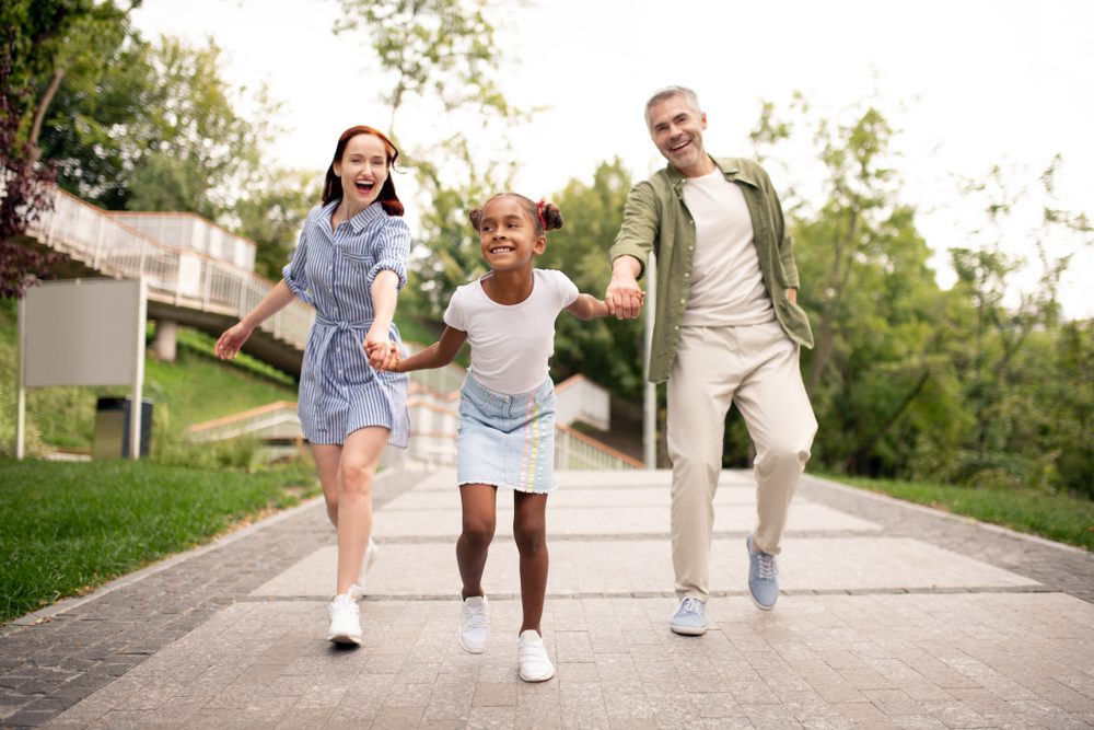 photo of two adults walking with a child