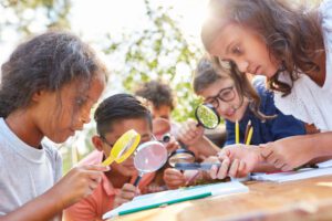 children with magnifying glasses out in nature